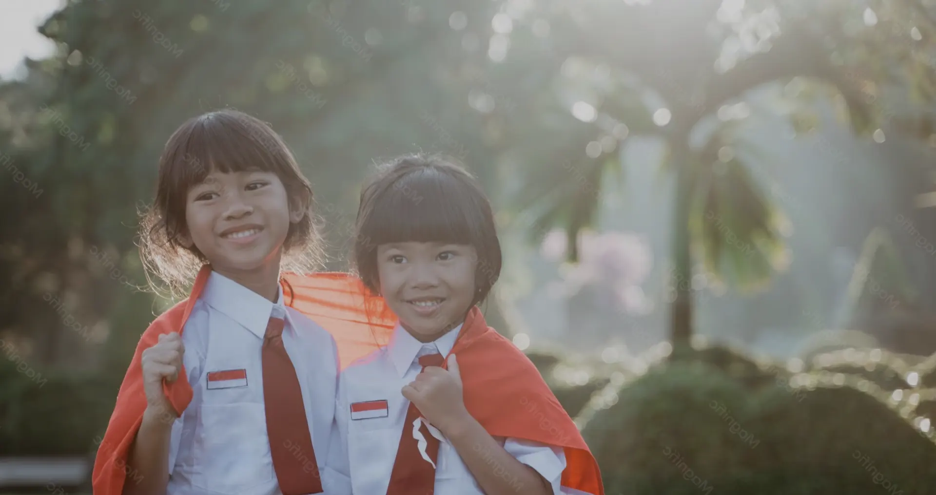 Dua siswa sekolah dasar tersenyum dengan seragam merah putih